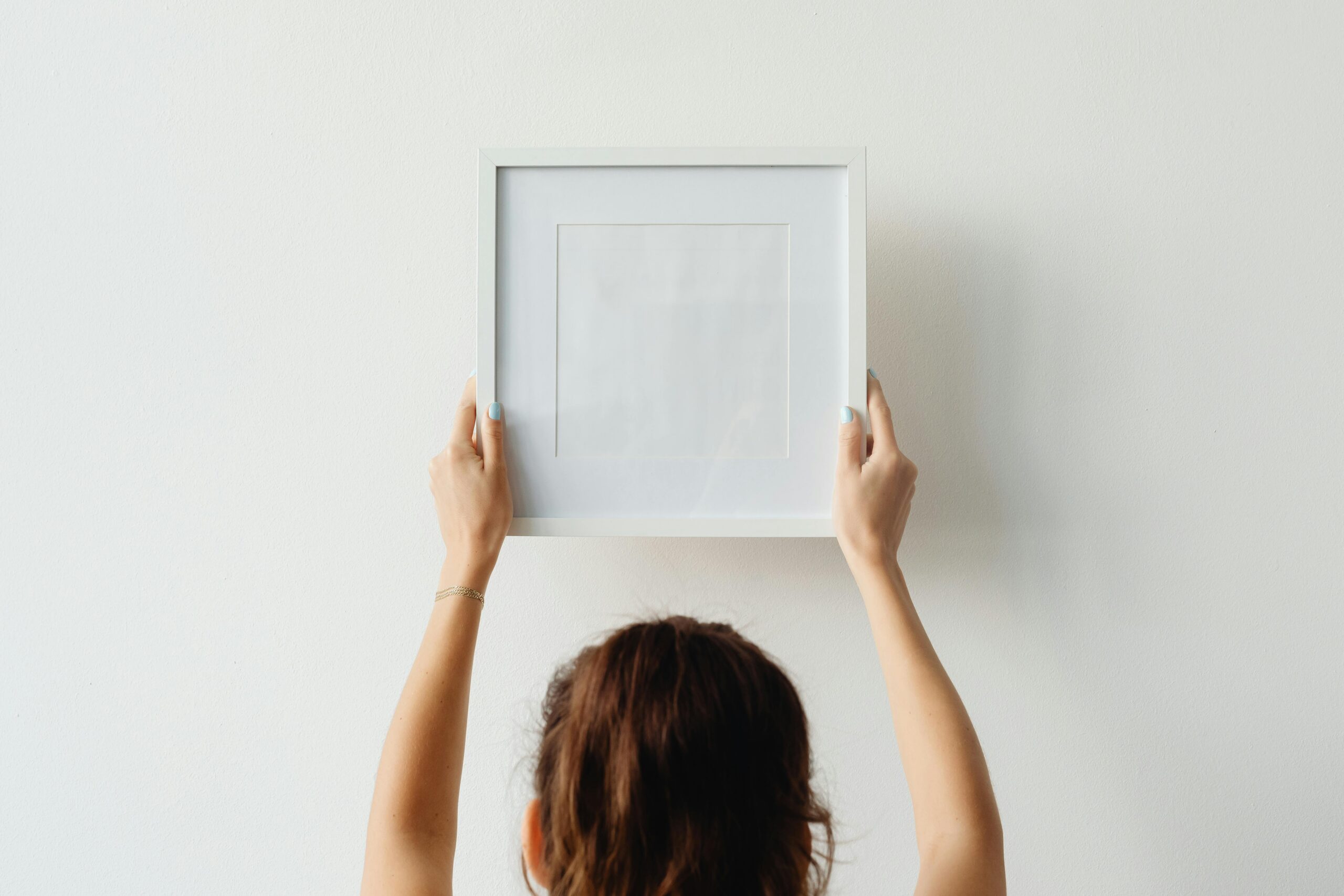Woman hanging framed wall decor in a modern home